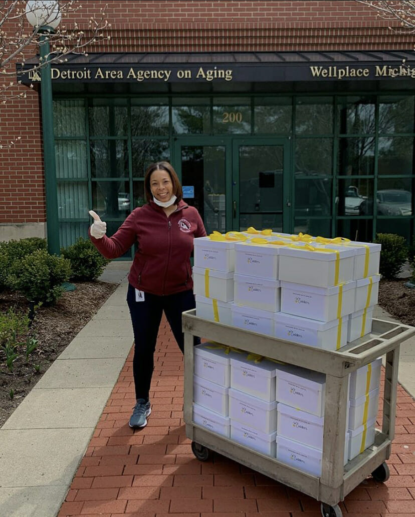 Detroit Area Agency on Aging staff member standing outside with a cart full of boxes.